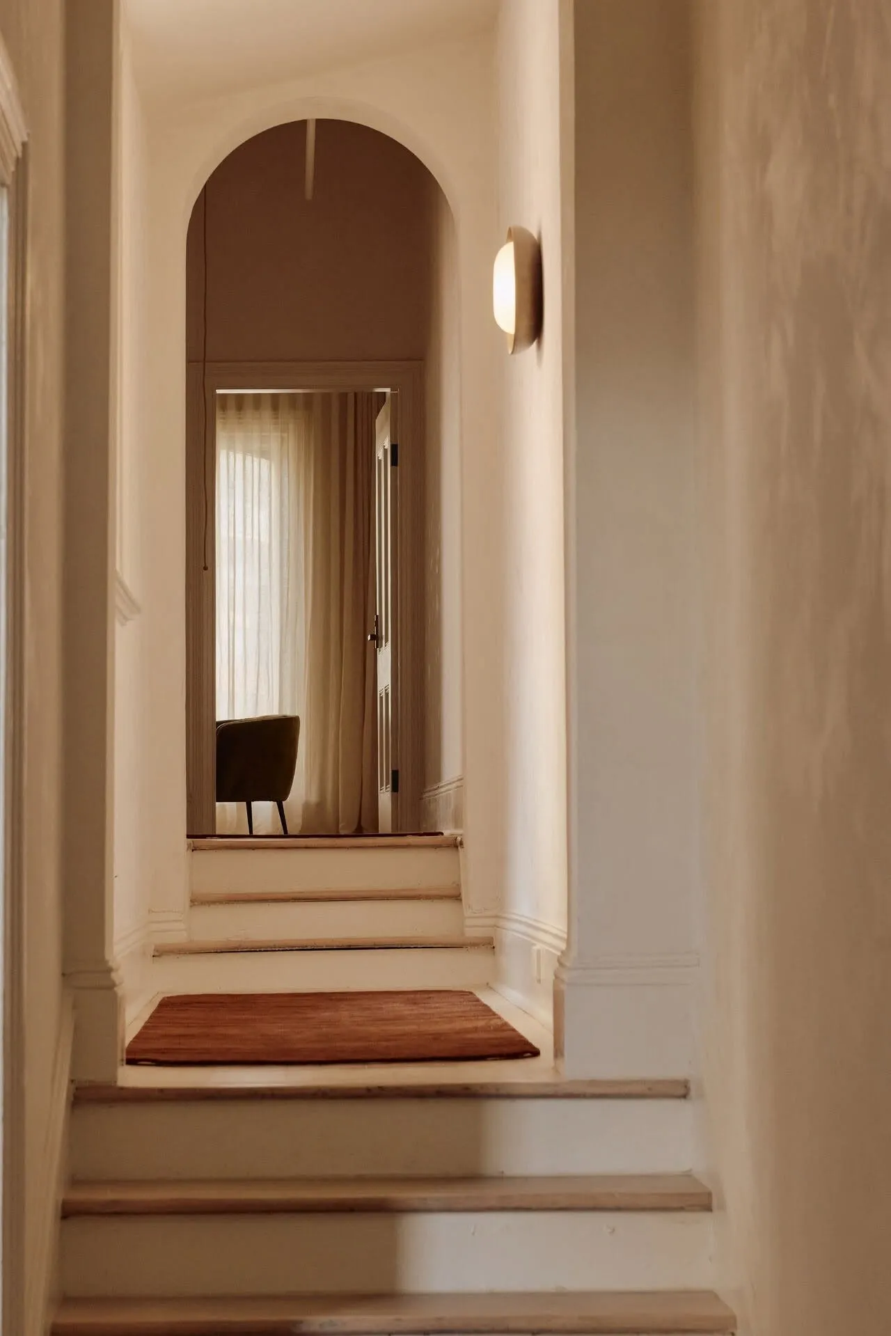 Steps leading up through an arched hallway to a sunlit room