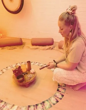 Kirsty kneeling in the studio beside a small altar inside a circle of cards