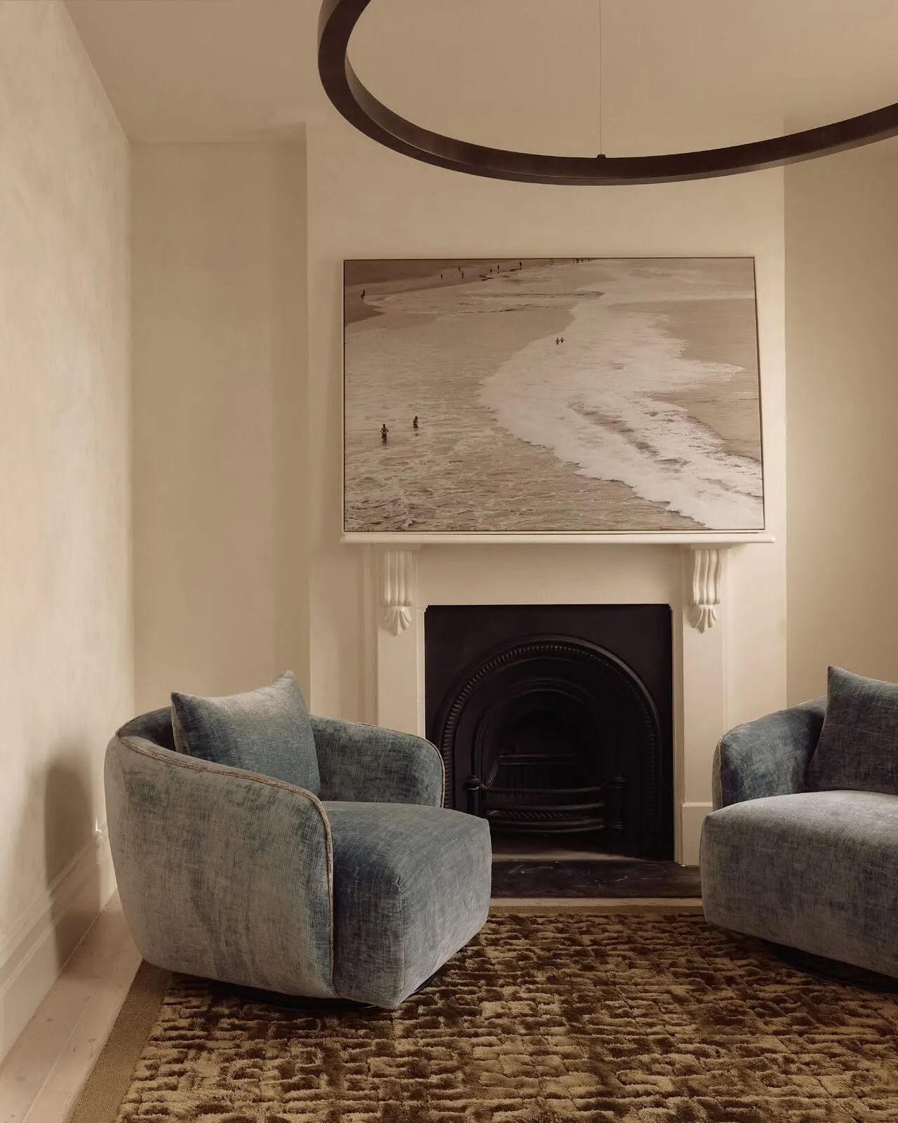 Two blue velvet armchairs in front of a heritage fireplace