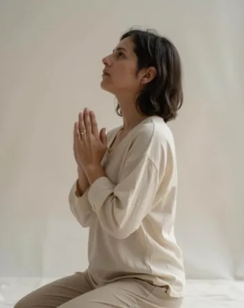 Sharon kneeling with her hands together, looking upward